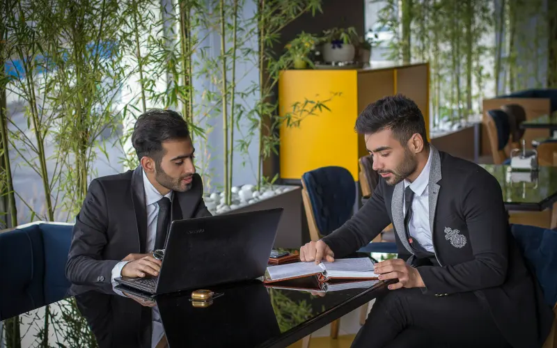 Two business partners in suits working together on a laptop